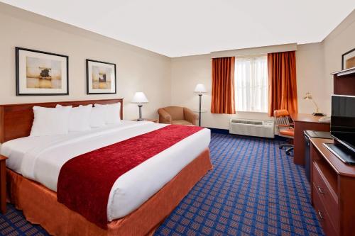 a hotel room with a large bed and a television at Baymont by Wyndham Grand Rapids SW/Byron Center in Byron Center