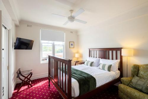 a bedroom with a bed and a tv and a chair at The Corner Hotel Alexandra in Alexandra