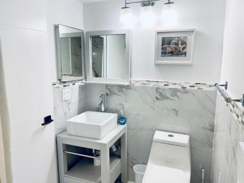 a white bathroom with a sink and a toilet at Ocean & Bay Views 2BR 2BA Beach Condo! Parking in Miami Beach