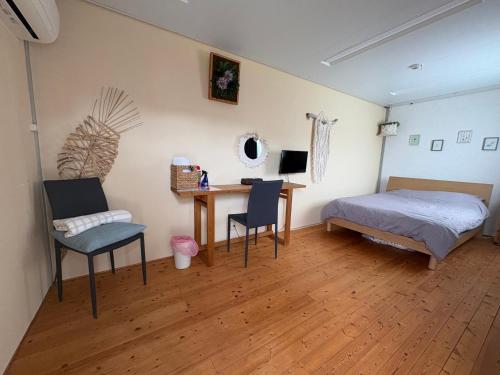 a bedroom with a bed and a desk and a bed and a table at 民宿あわい in Nakijin