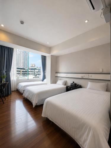 two beds in a hotel room with a window at Fudi Hotel in Taichung