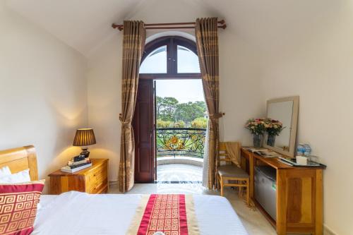 a bedroom with a bed and a desk and a window at Xuan Truong Central Dalat-1 min walk to Xuan Huong Lake in Da Lat