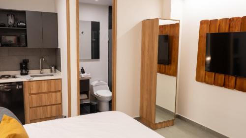 a room with a bathroom with a bed and a television at Once Suites in Envigado