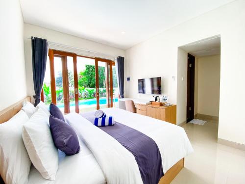 a bedroom with a large bed with white and purple pillows at Casa de Ambalia in Uluwatu