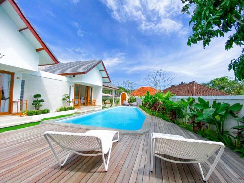 a wooden deck with two chairs and a swimming pool at Casa de Ambalia in Uluwatu