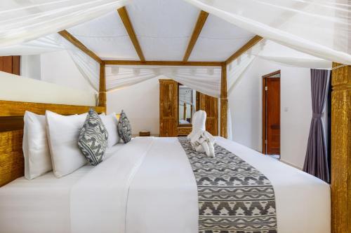a bedroom with a large white bed with pillows at Ubud Mesari Private Pool Villa in Ubud