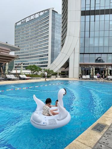 two children riding on an inflatable swan in a pool at Hyatt Regency Hengqin in Zhuhai