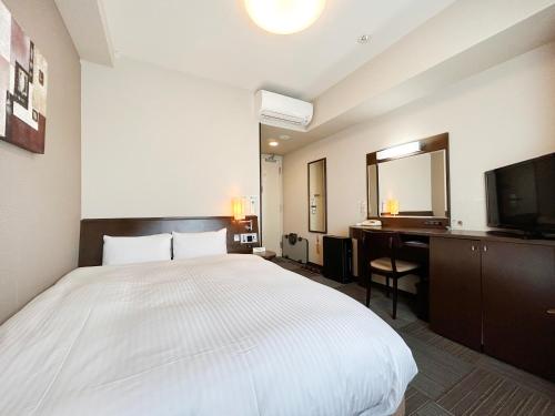 a bedroom with a bed and a desk and a television at Hotel Route-Inn Nobeoka Ekimae in Nobeoka