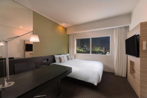 a hotel room with a bed and a desk and a window at Palace Hotel Omiya in Saitama
