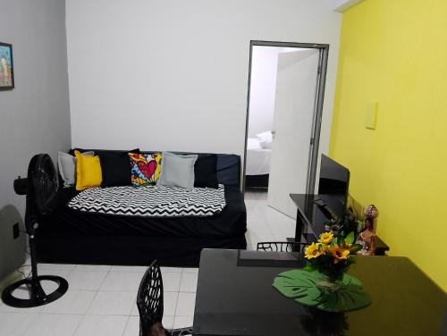 a living room with a black couch and a mirror at Kitnet mobiliado a minutos do Parque do Povo in Campina Grande