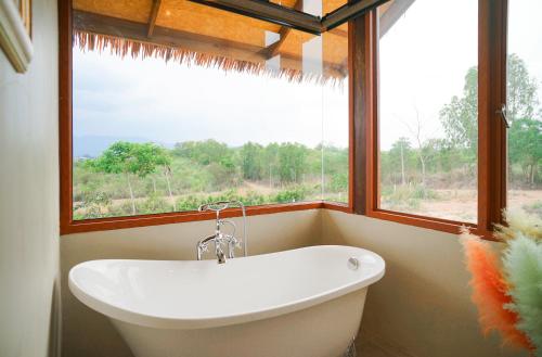 a bath tub in a bathroom with a large window at Baannok at Motakhian in Pak Chong