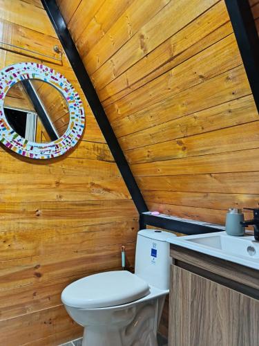 a bathroom with a toilet and a wooden wall at Glamping Jadiva in Cucunubá