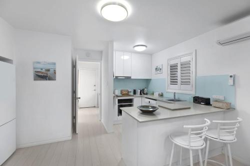 a kitchen with white counters and white cabinets and white stools at Applecross - Perfect For A Weekend Escape in North Avoca