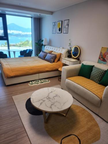 a living room with a bed and a couch and a table at 히얼마리나 in Ungch'ŏn-ni
