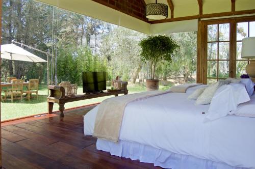 Un dormitorio con una gran cama blanca y una mesa en La Palma Polo Hotel - Airport Area en Puembo