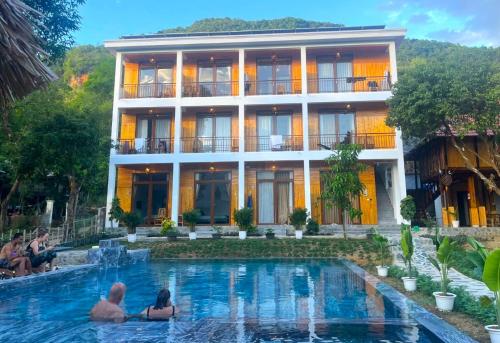 a man and woman sitting in front of a hotel at Meadow Mai Chau Homestay in Mai Châu