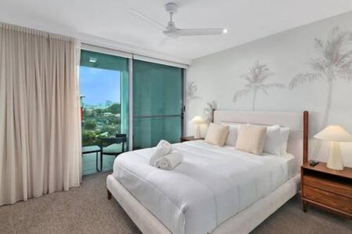 a bedroom with a white bed and a large window at Picnic Point Panoramic Views in Maroochydore