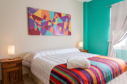 Las Tulmas Apartamentos Salta في سالتا: غرفة نوم بسرير ودهان على الحائط