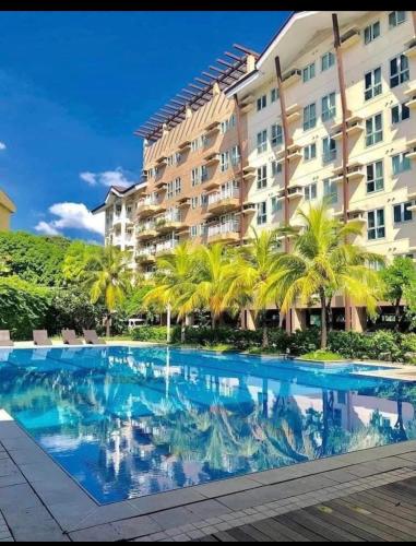 a swimming pool in front of a building with palm trees at Rochester Garden Condo in Manila
