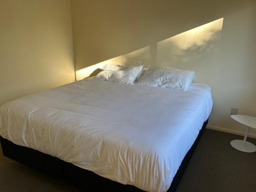 a bedroom with a bed with white sheets and pillows at The Raukawa Cottage in Tauranga