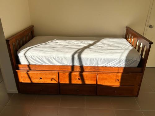 a bedroom with a wooden bed with a white sheets at The Raukawa Cottage in Tauranga