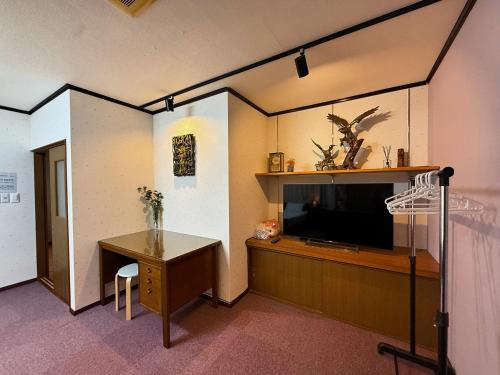 a room with a tv and a desk and a table at Ema-長吉 in Osaka