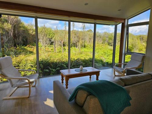 a living room with a couch and chairs and a table at Fern View - Cozy 2-bedroom house in Hokitika