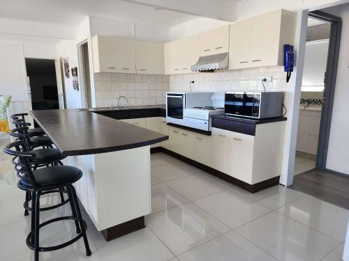 a kitchen with white cabinets and a black counter top at Mollymook Beach Haven - near ocean & golf course in Mollymook