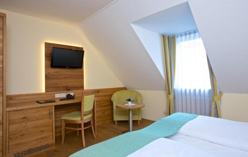 a hotel room with a bed and a desk and a tv at Hotel am Schloßberg in Erding