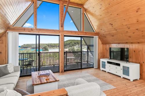 a living room with a tv and a large window at Sea-renity in Kioloa