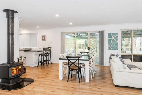 a living room with a fireplace and a table and a stove at The Salty Deck in Narrawallee