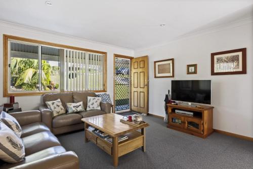 a living room with a couch and a tv at Jillby's House - 3 BR home near Narrawallee Beach in Narrawallee