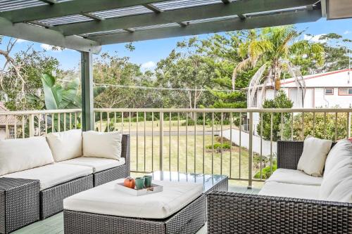 a patio with two couches and a glass table at The Salty Deck in Narrawallee