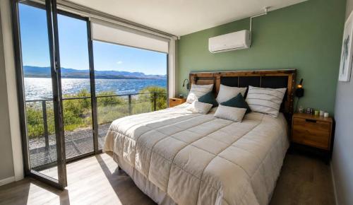 a bedroom with a large bed with a large window at Lakefront, Jacuzzi and Pool in San Carlos de Bariloche