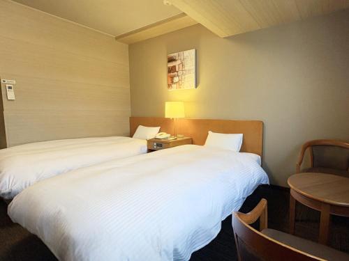 a hotel room with two beds and a table at Hotel Route-Inn Suwa Inter in Suwa
