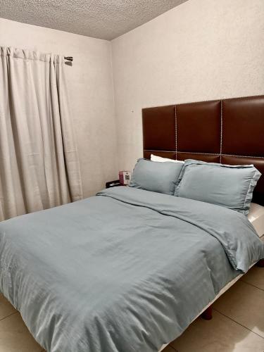 a bedroom with a large bed with a brown headboard at Casa privada con estacionamiento in Hermosillo