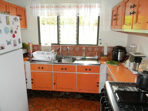 cocina con armarios de color naranja y fregadero en Habitacion Santo Domingo, Heredia en Santo Domingo