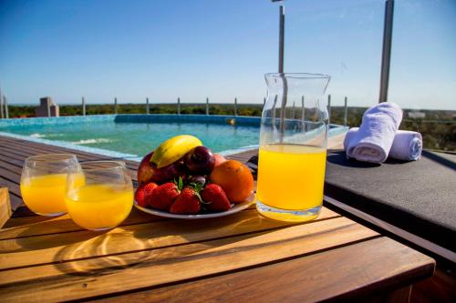 a plate of fruit and two glasses of orange juice on a table at Hotel Zentiva Pinamar in Pinamar