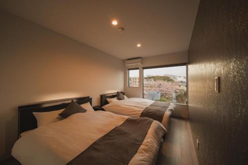 a bedroom with two beds and a large window at 湯宿 蒼の月 in Oita