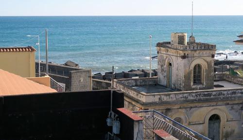 an old building with the ocean in the background at Scariceddu in Riposto