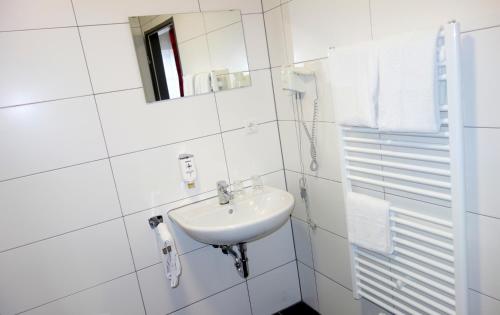 a white bathroom with a sink and a mirror at Budget Hotel Ludwigshafen in Ludwigshafen am Rhein