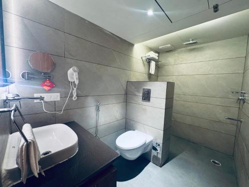 a bathroom with a toilet and a sink and a phone at Hotel Vaishnavi Heights in Aurangābād
