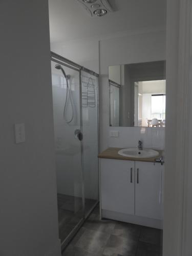 a white bathroom with a shower and a sink at Kingston Foreshore Caravan Park in Kingston South East
