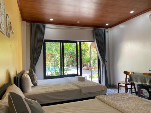 a bedroom with two beds and a large window at Tam Coc Harmony Homestay in Vũ Lâm