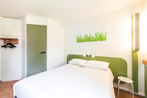 a bedroom with a white bed and a green wall at ibis budget Châtellerault Nord in Châtellerault
