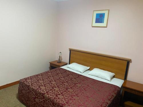 a bedroom with a red bed with two pillows at Hotel Al Masa in Al Buraymī