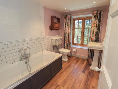 a bathroom with a tub and a toilet and a sink at Rose Cottage Coniston in Coniston