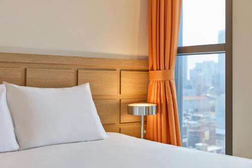 ein Bett mit einem weißen Kissen und einem Fenster in der Unterkunft Hotel POCO Seongsu in Seoul