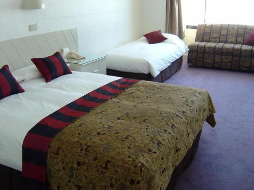 a hotel room with two beds and a couch at Perisher Manor Hotel in Perisher Valley