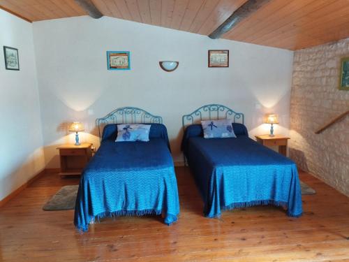 two beds in a room with blue sheets at Le Logis de bouillé in Bouillé-Courdault